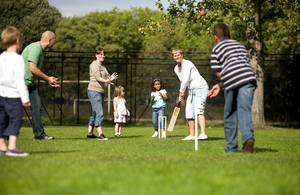 Group of people of different ages playing cricket in a garden