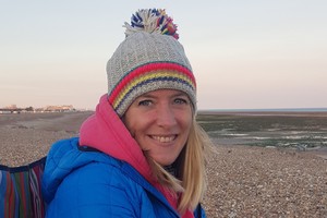 Sophie Goodall-Smith sitting on a beach with a woolly hat on