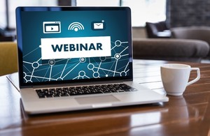 Picture of a computer on the desk showing the word webinar on the screen