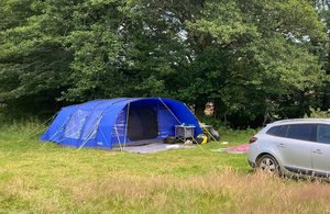A large blue tent pitched in a grassy field
