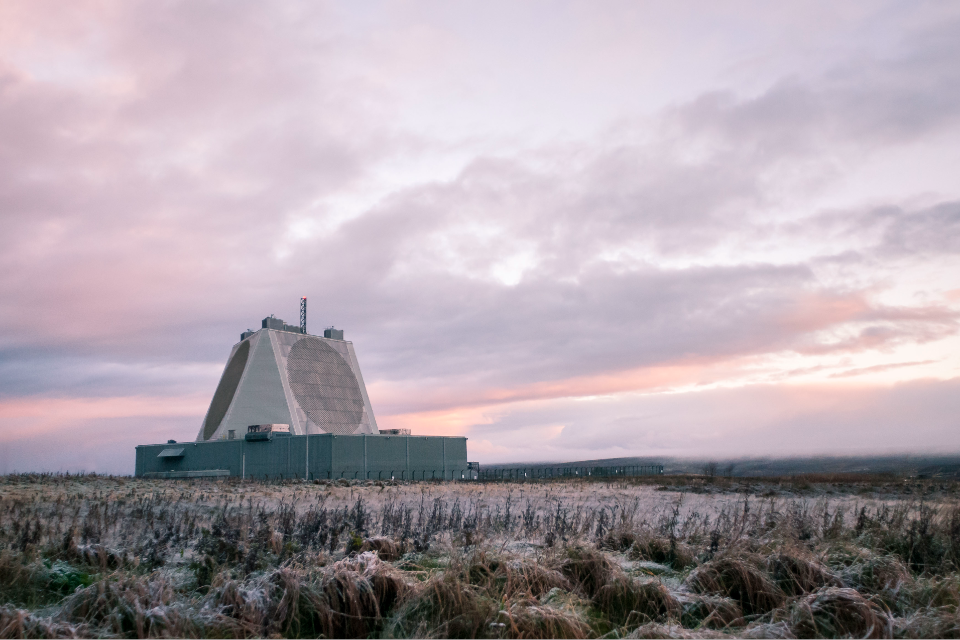 A grey building against a pink sky.