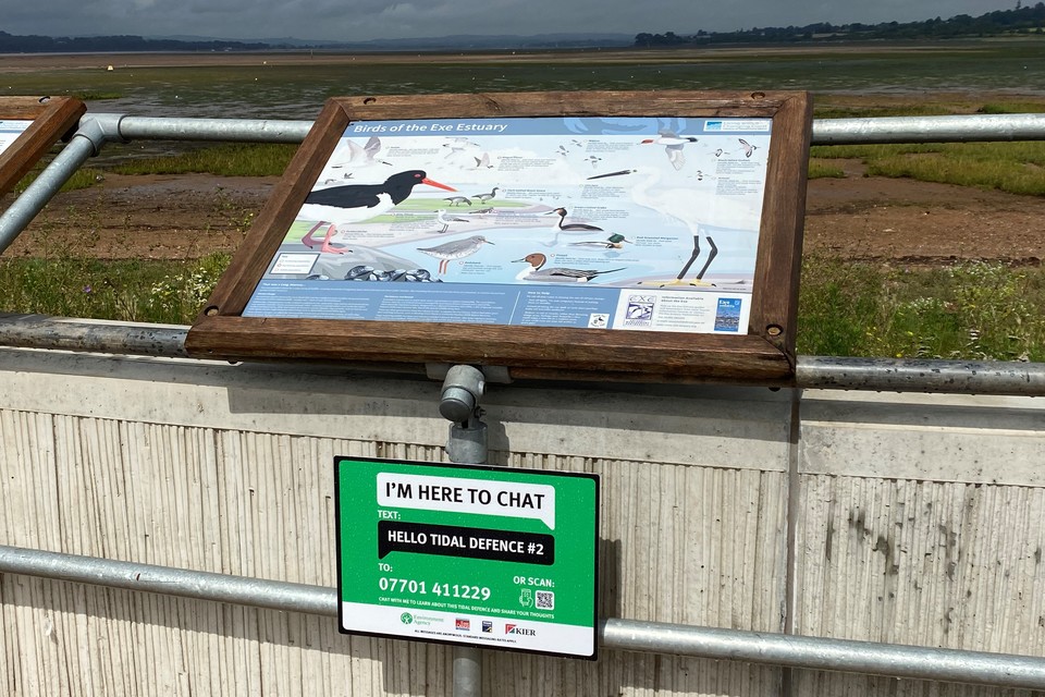 Sign saying I'm here to chat with number you can text for information about the Exmouth tidal defence scheme