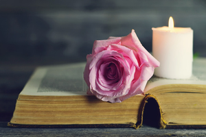a rose and a candle on top of a book.