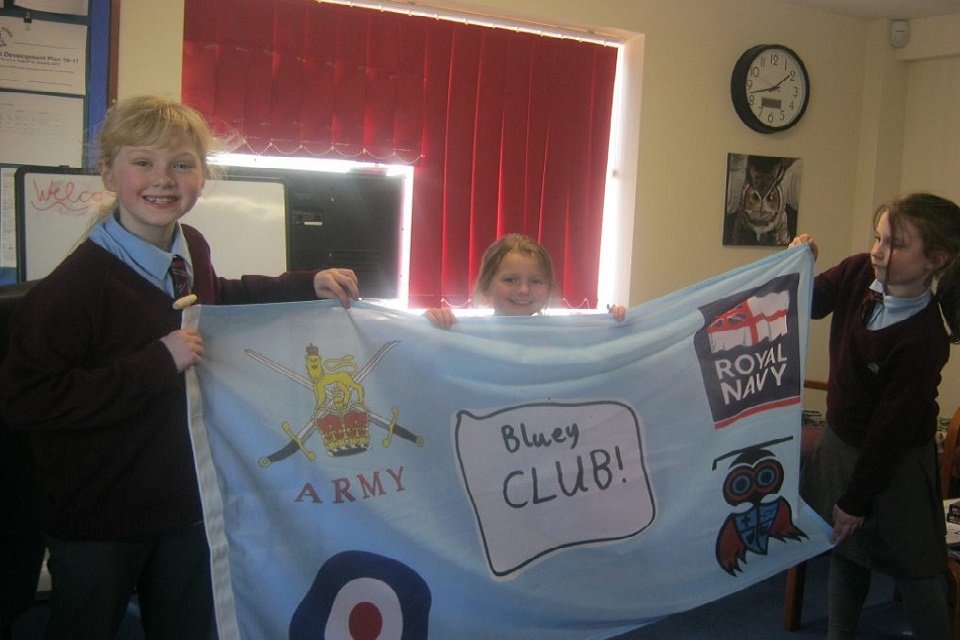 3 child Bluey Club members hold up a flag