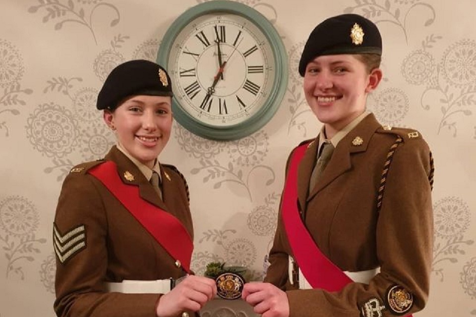 Cerys and Tegan in uniform holding an award. 