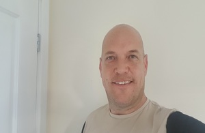 A photograph of Michael Wright wearing a blue t shirt and looking directly into the camera.