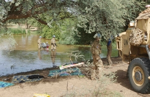 British soldiers in blue UN helmets tow a motorcycle out of a body of water after a suspected jihadist tried to escape
