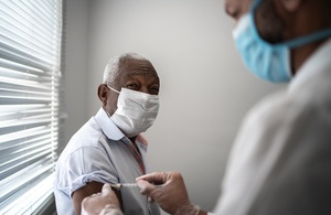 Older man in mask receiving his COVID-19 vaccination.