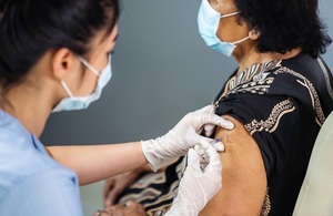 Doctor in gloves vaccinating an older woman.