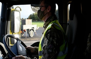 A former service person sits in the driver's seat of a heavy goods vehicle with a mask on