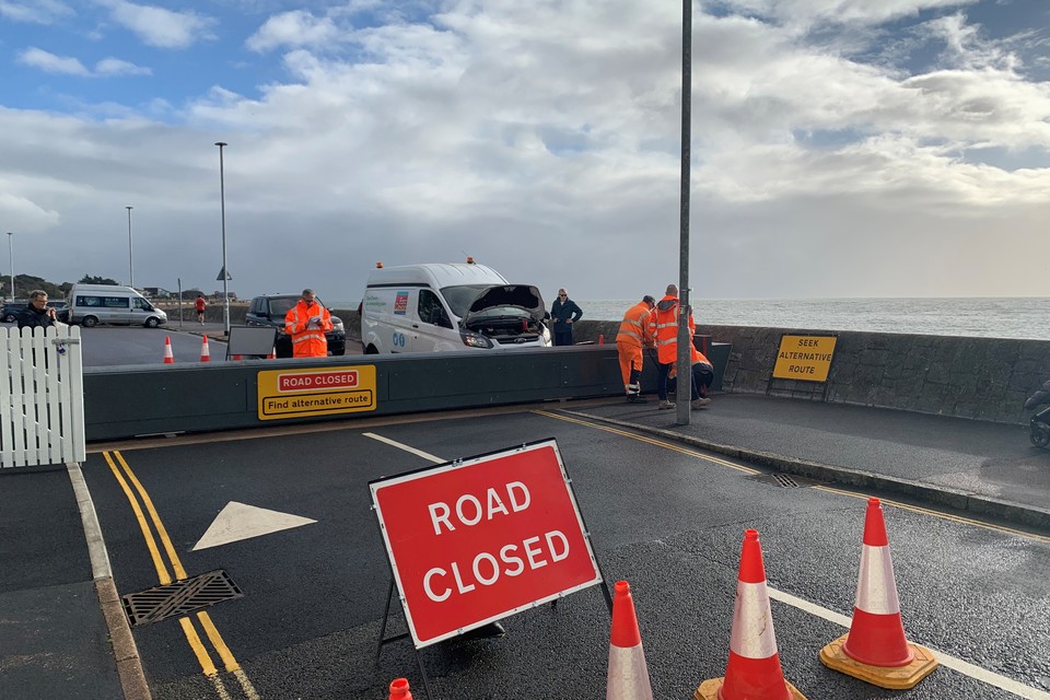 Road closed sign in front of a flood gate closing the sea front at Exmouth