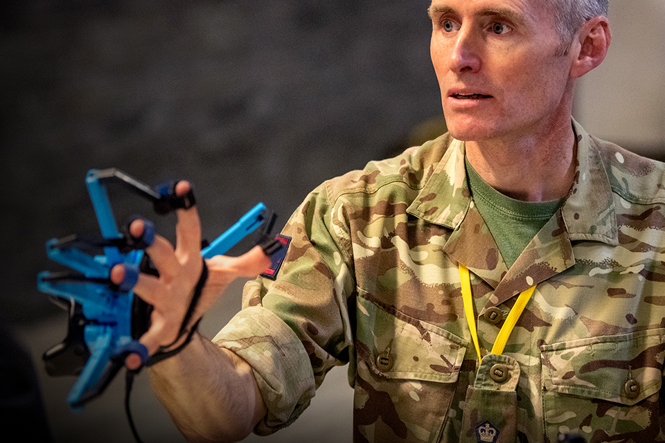 Person in army uniform tries out glove to remotely control robotic hand