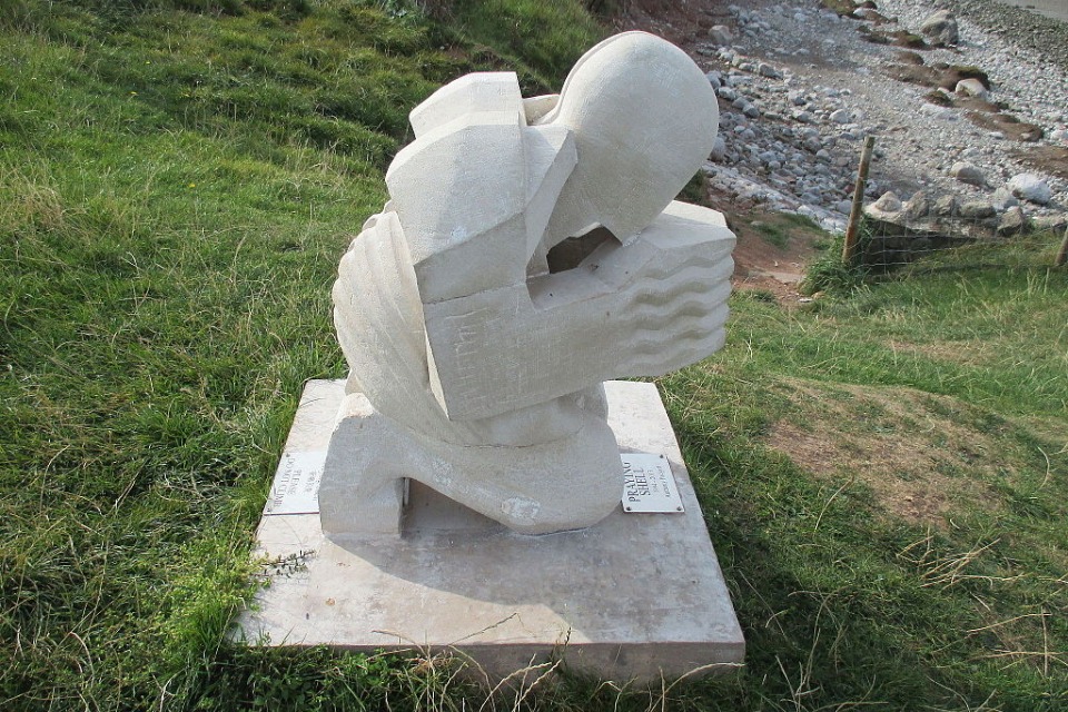The 'Praying Shell ' artwork overlooking Morecambe Bay. A white stone figure of a person praying.  