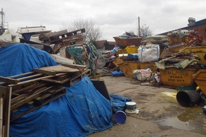 Piles of waste, including a skip, wood, pallets and bags of rubbish