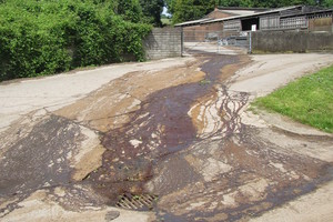 Dark stains on a concrete road leading up to farm buildings