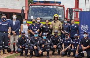 A group of approximately 15 people pose in front of a fire engine truck