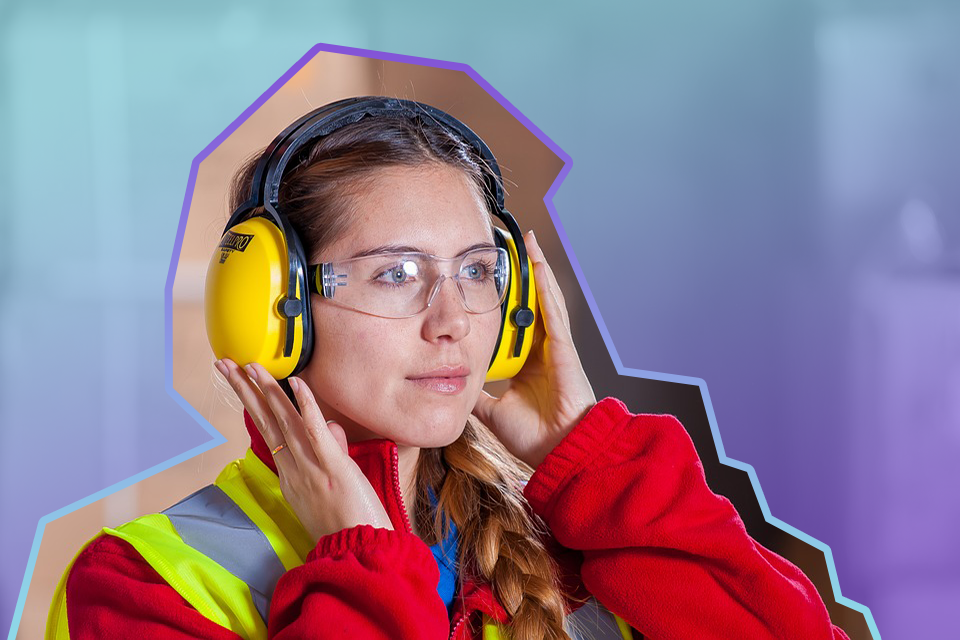 A female vocational qualification student adjusting her ear defenders during a practical assessment.