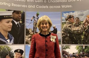 Lady smiling and standing in front of a military backdrop.