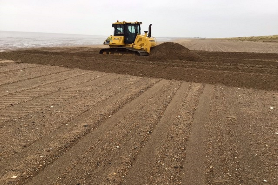 A construction vehicle moving the sand. 