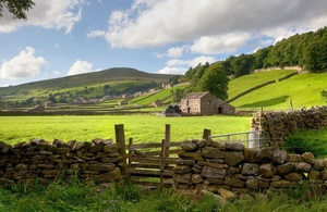 Farmland, including a stone wall and farmhouse in the distance