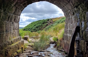 looking through a tunnel to a landscape of green hills and blue sky