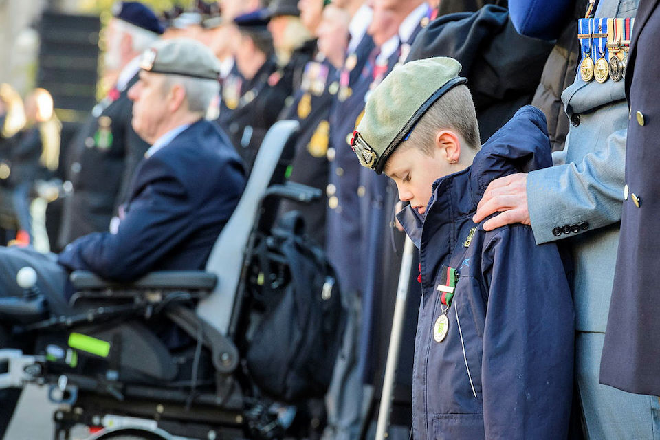 Child stands with hand on shoulder from family as he remembers loss of a loved one.