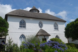 Большой дом в коттеджном стиле с соломенной крышей, белыми стенами и маленькими окнами