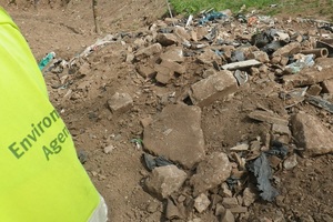 Environment Agency officer inspecting a heap of rubble and waste
