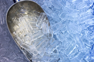 A silver ice shovel in a tray of ice cubes 