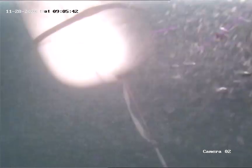 Still from dive survey video showing that the liferaft had been released from the cradle and was floating, uninflated at the end of the painter. The bottom of the canister can be seen in the top-left of the image