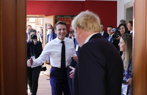 Boris Johnson and President Macron smile and walk towards each other to shake hands.