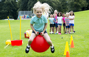 Girl on space hopper in playing field.