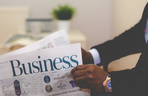Man in a suit holding the business edition of a newspaper.