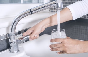 Person filling glass with drinking water from tap.