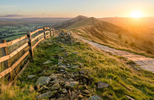 Hilly landscape and a wooden fence on the left hand side of the image