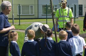 School children watching a man planting tree on a field