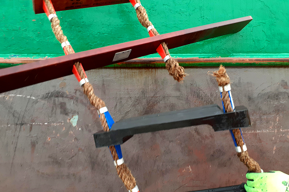 Close-up of broken rope on the right side of a pilot ladder. The ladder's identification plate is visible on the underside of the longest step