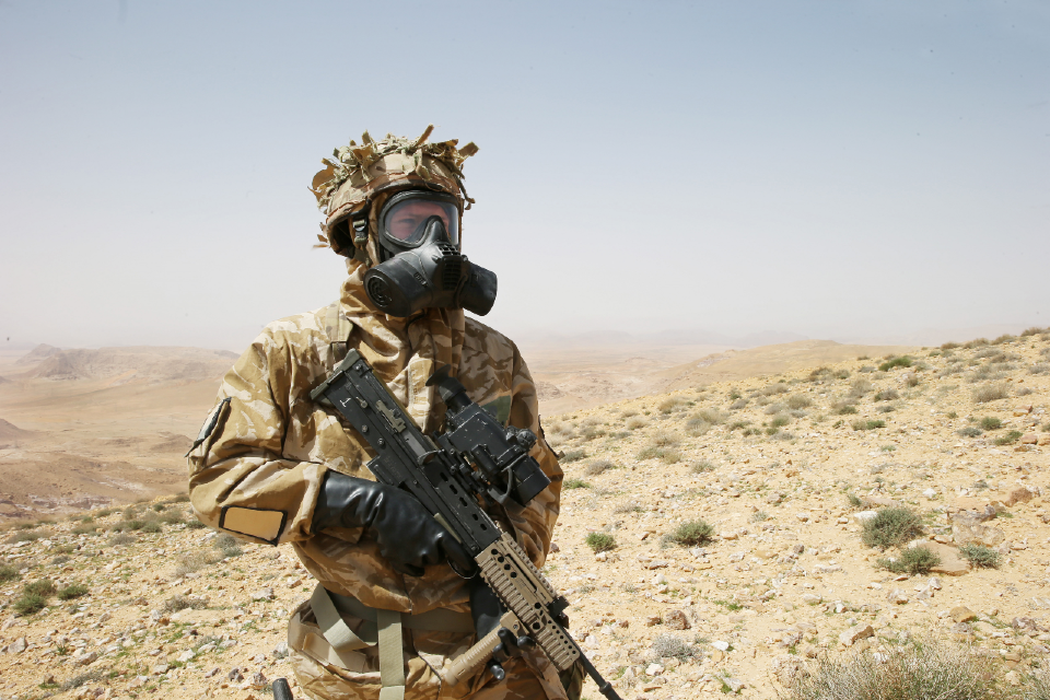 Member of the armed forces holding a gun and wearing protective gear including mask