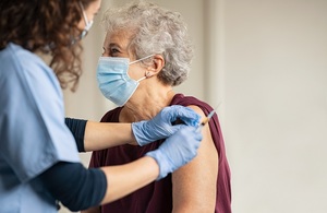 Older woman receiving a COVID-19 vaccine injection by a health care professional.