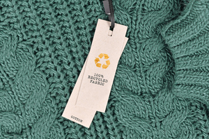 Green knitted jumper with a tag attached saying 100% recycled fabric
