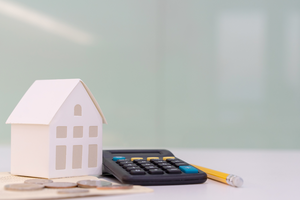 Model of a house with calculator and money