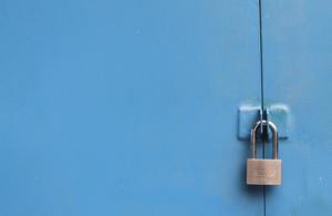 A padlock securing a blue gate.