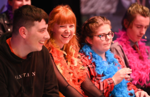 Young people from Youth Action NI are pictured smiling and sitting side-by-side.