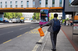 Young person putting their arm out to request a bus stops