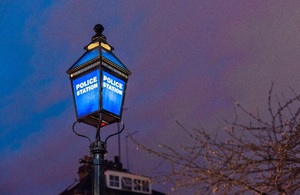 Blue police station shining against a night sky