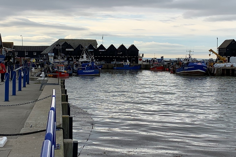 Image shows fishing boats moored in small harbour