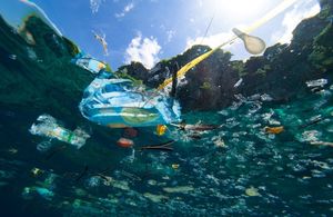 Plastic rubbish floating in the ocean with blue skies above