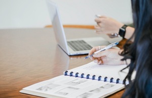 Woman with long black hair writing in a notebook