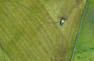 farmer spraying slurry on a green field viewed from above