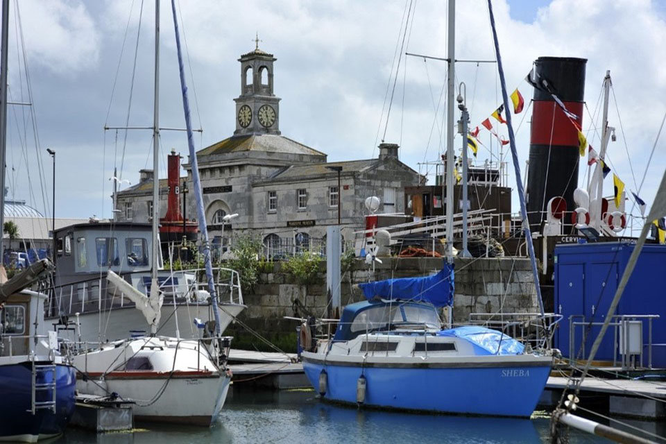 Seafront view of the Clock House building with boats moored in the foreground